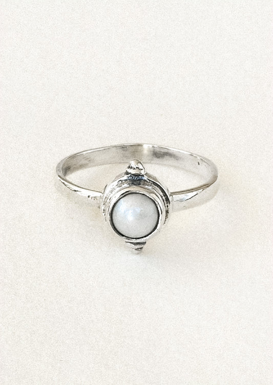 A sterling silver ring with a faux pearl in the center.