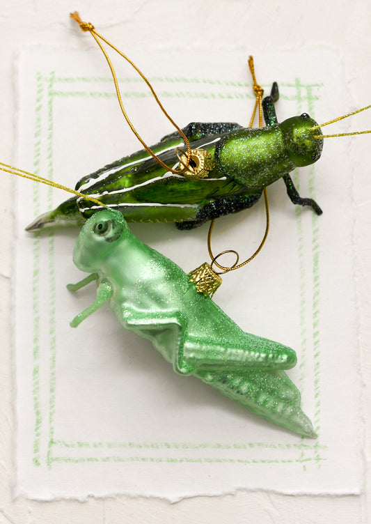 Glass grasshopper ornaments in dark green and light green options.