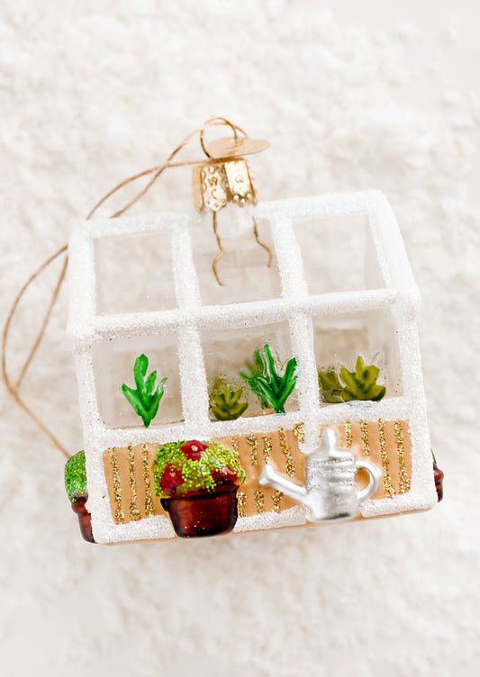 A decorative glass holiday ornament of a glass greenhouse.