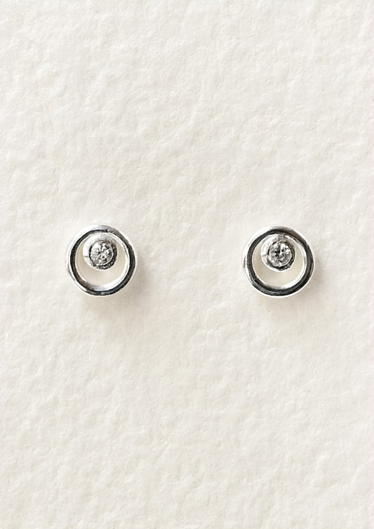 A pair of sterling silver circle stud earrings with a tiny crystal in the center.
