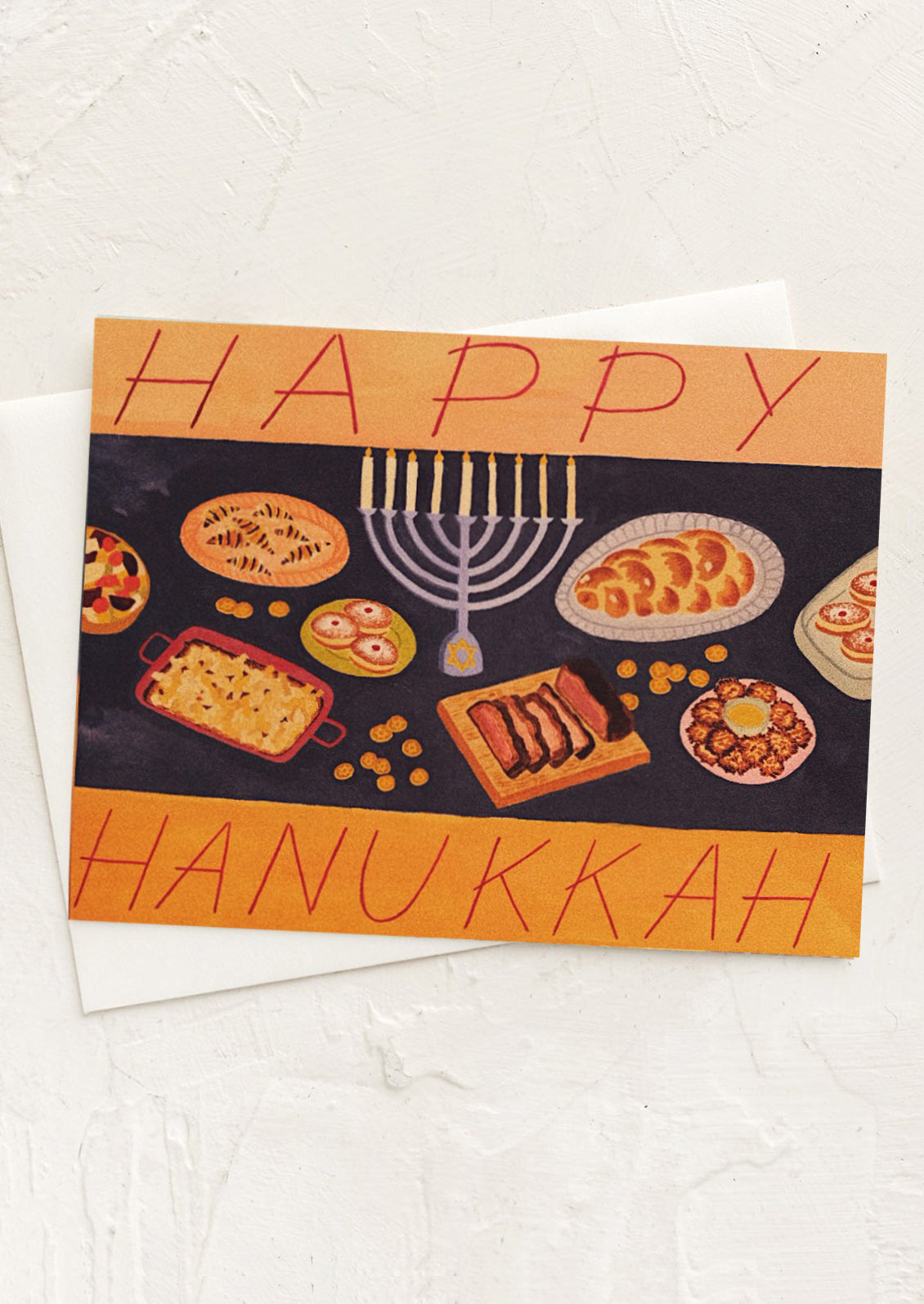 A greeting card with illustration of food on a table, text reads "Happy Hanukkah".
