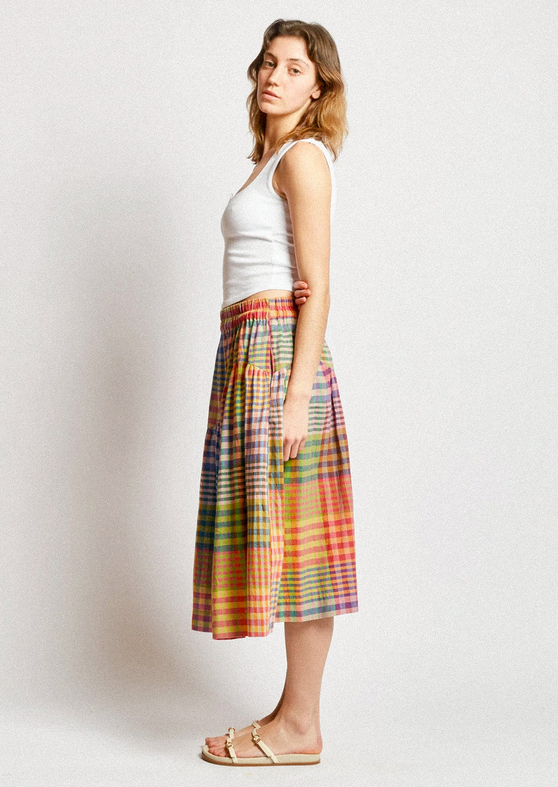 A person wearing a cotton skirt in colorful plaid.