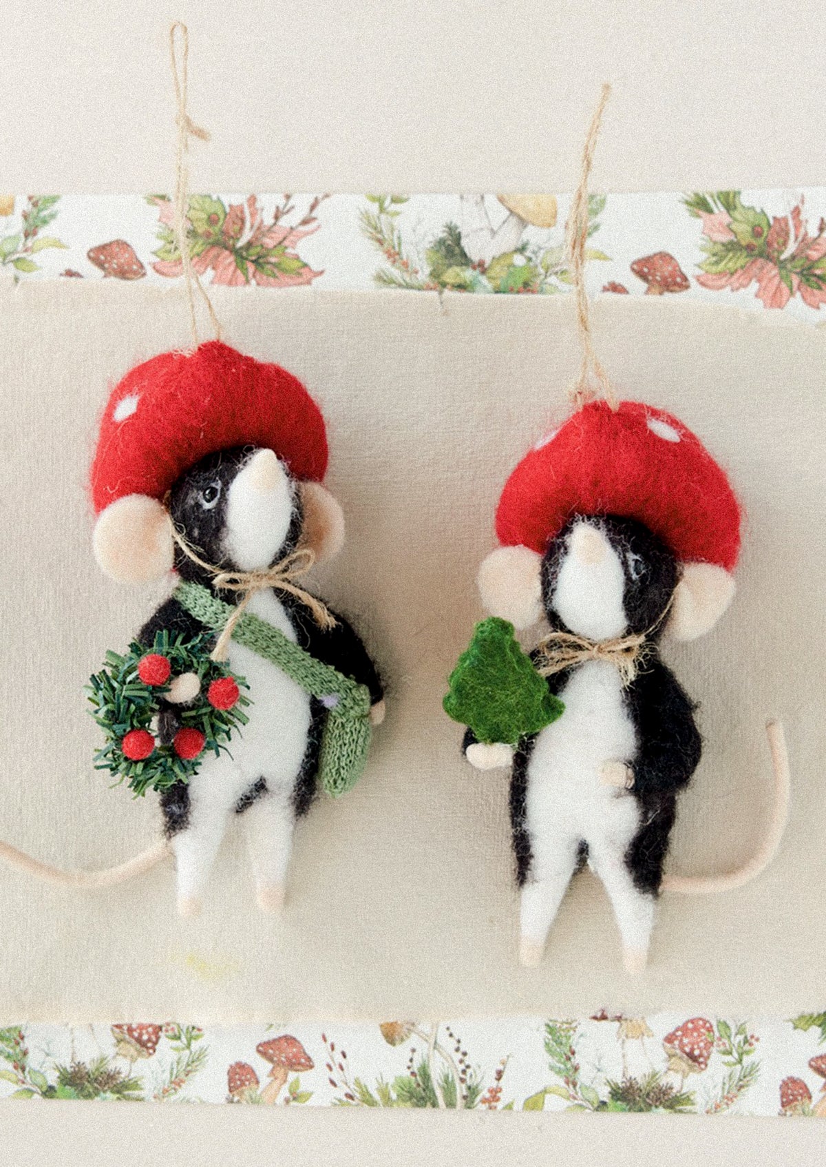 Wool felt ornaments of moles wearing toadstool hats and holding a wreath and a small tree, respectively.