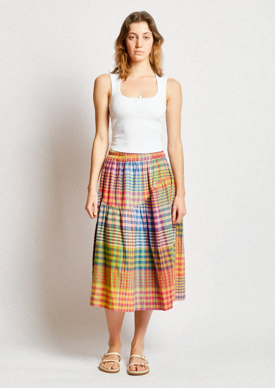 A person wearing a cotton skirt in colorful plaid.