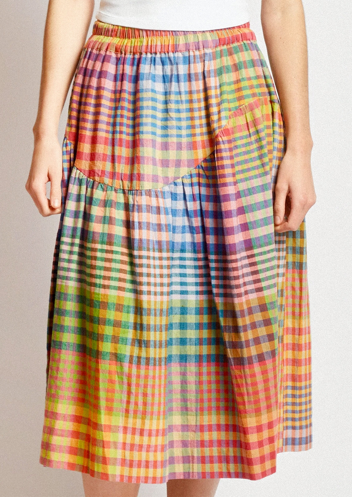 A person wearing a cotton skirt in colorful plaid.