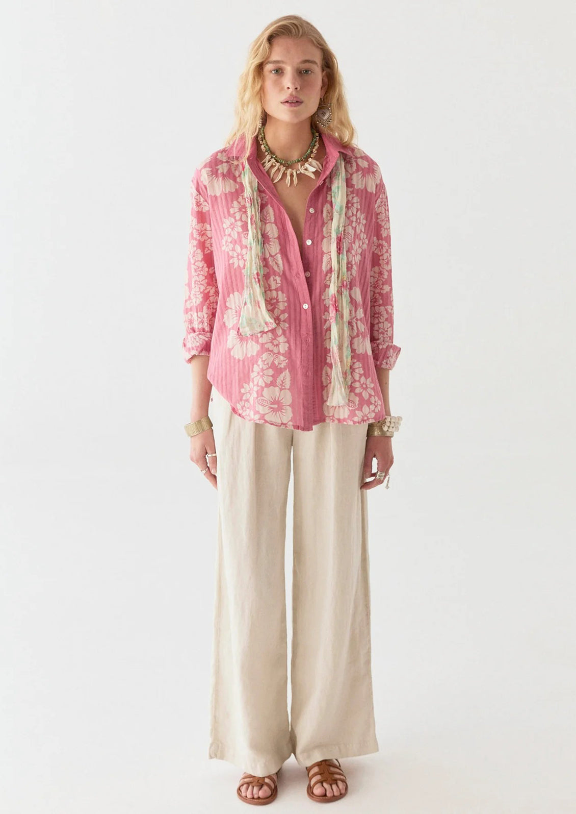 A person wearing a pink cotton shirt with tonal pinstripes and Hawaiian floral pattern.