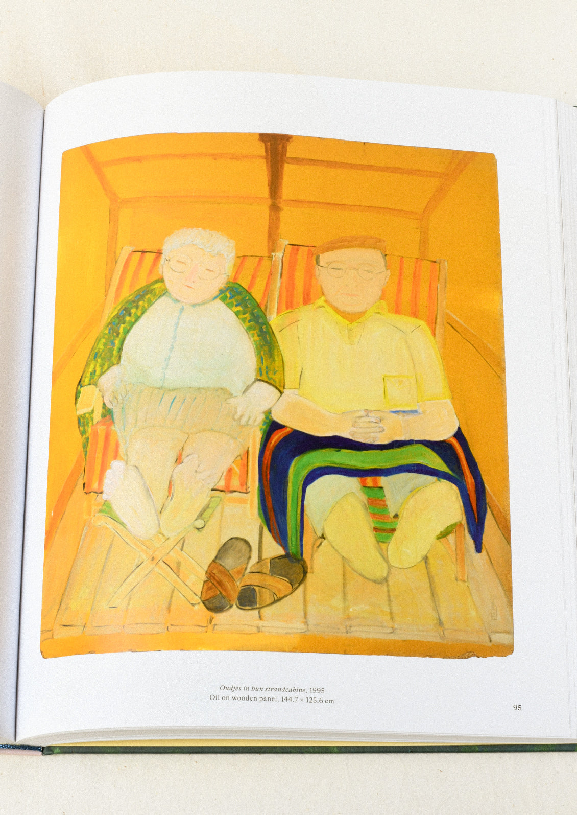 An open book lying flat on a table showing an oil painting of a older man and woman sitting in chairs with an orange background.