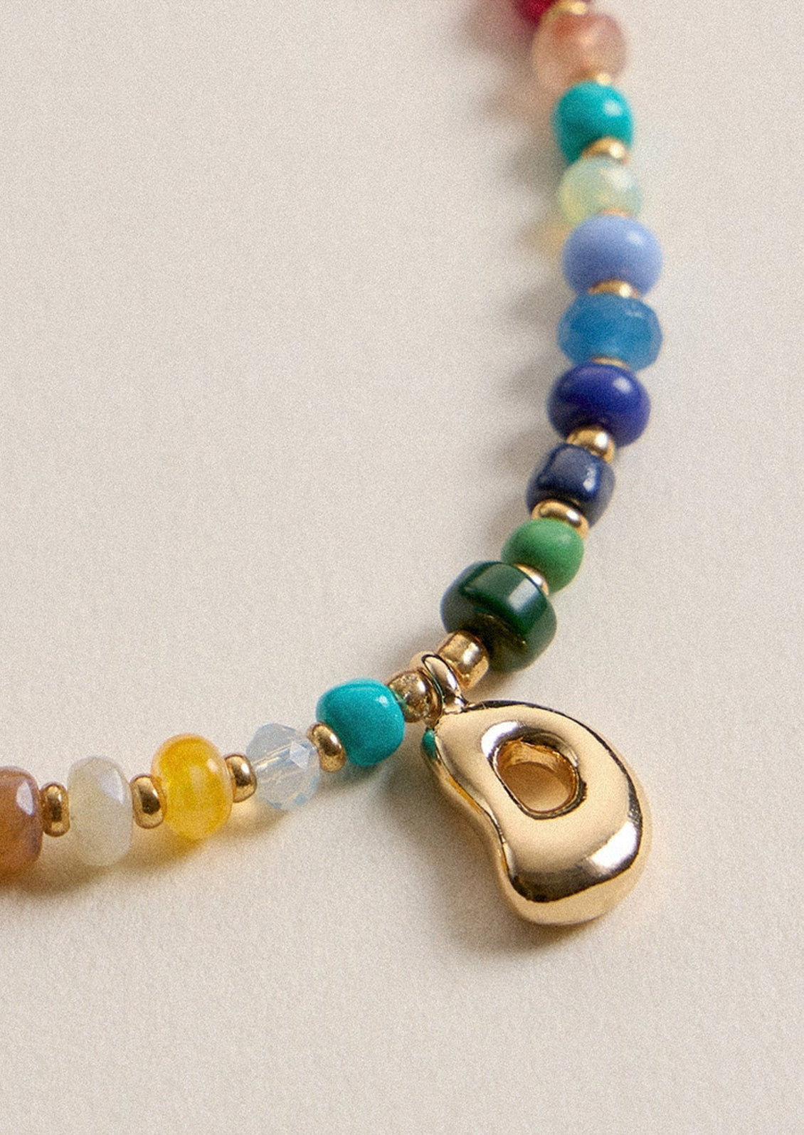 A colorful beaded necklace with a gold D charm.