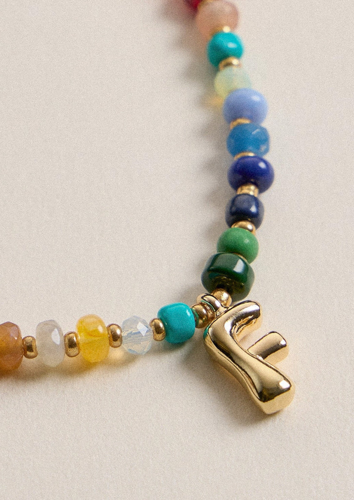 A colorful beaded necklace with a gold F charm.
