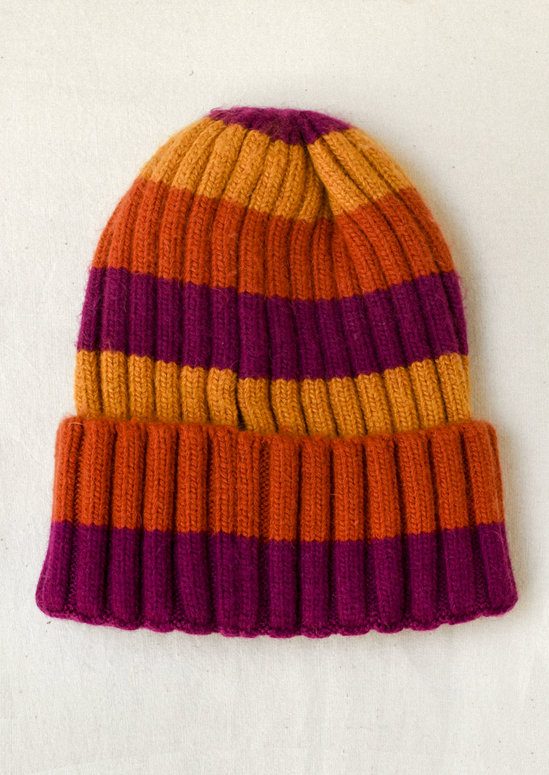A cashmere-blend ribbed beanie with magenta, yellow, and orange stripes.