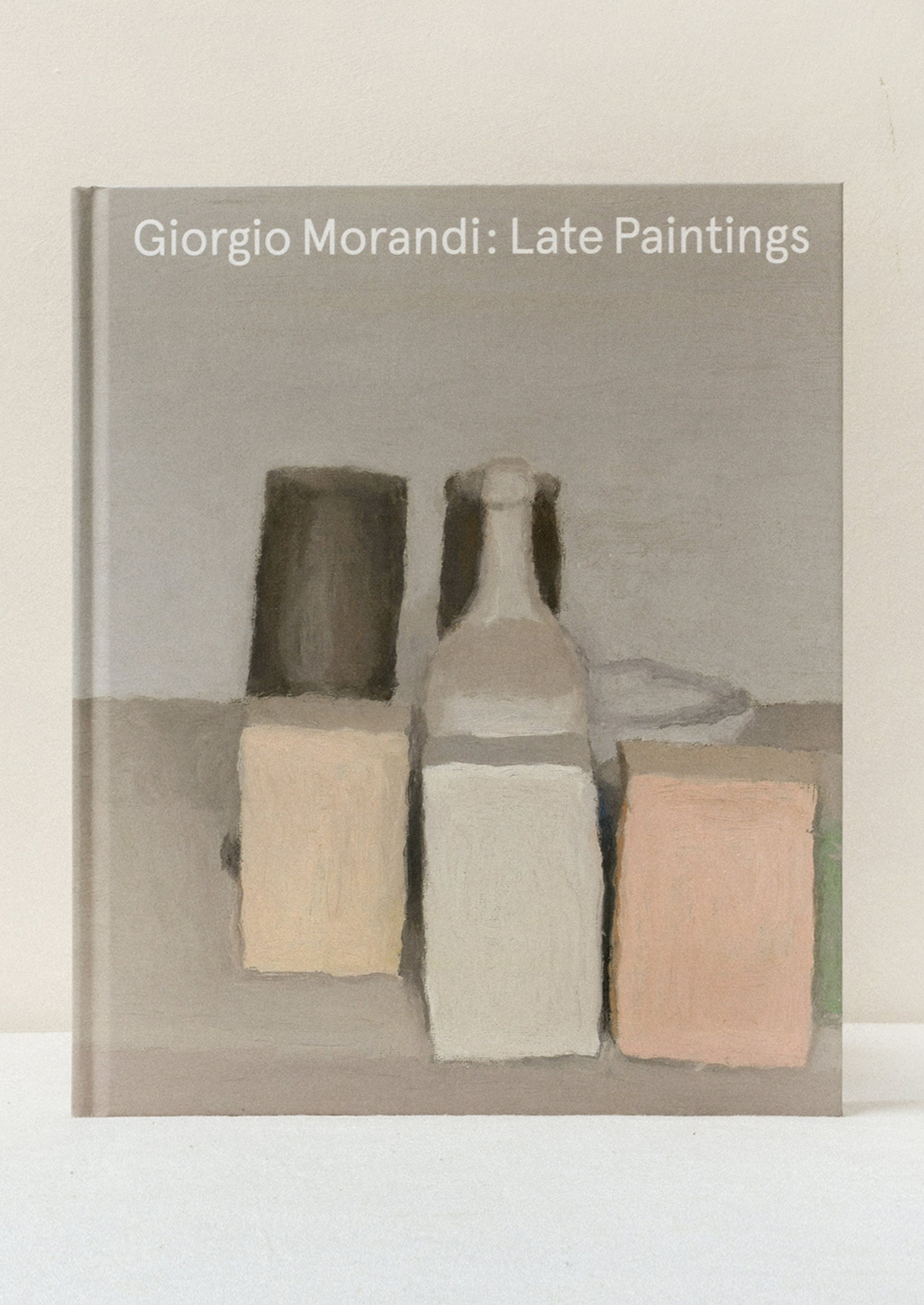 A hardcover book standing on a table titled "Giorgio Morandi: Late Paintings" with one of his paintings on the front.