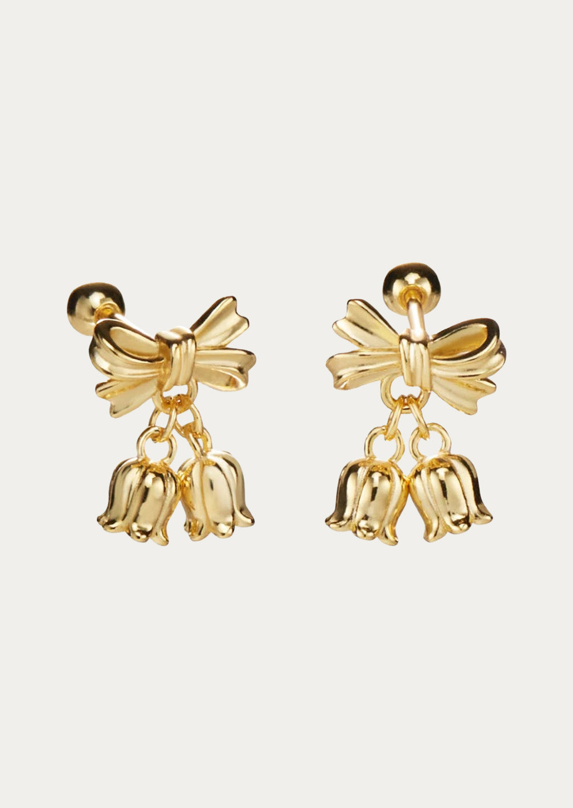 A pair of gold earrings in the shape of a bow with two lily of the valley flower charms dangling at the ends.