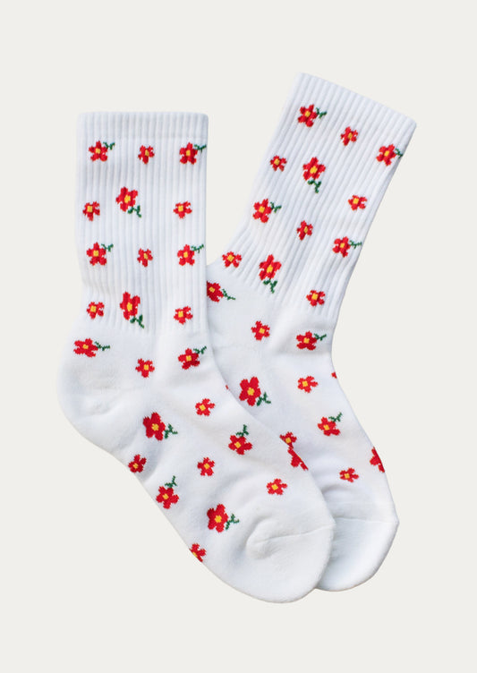A pair of white ribbed crew socks with little red flowers throughout.