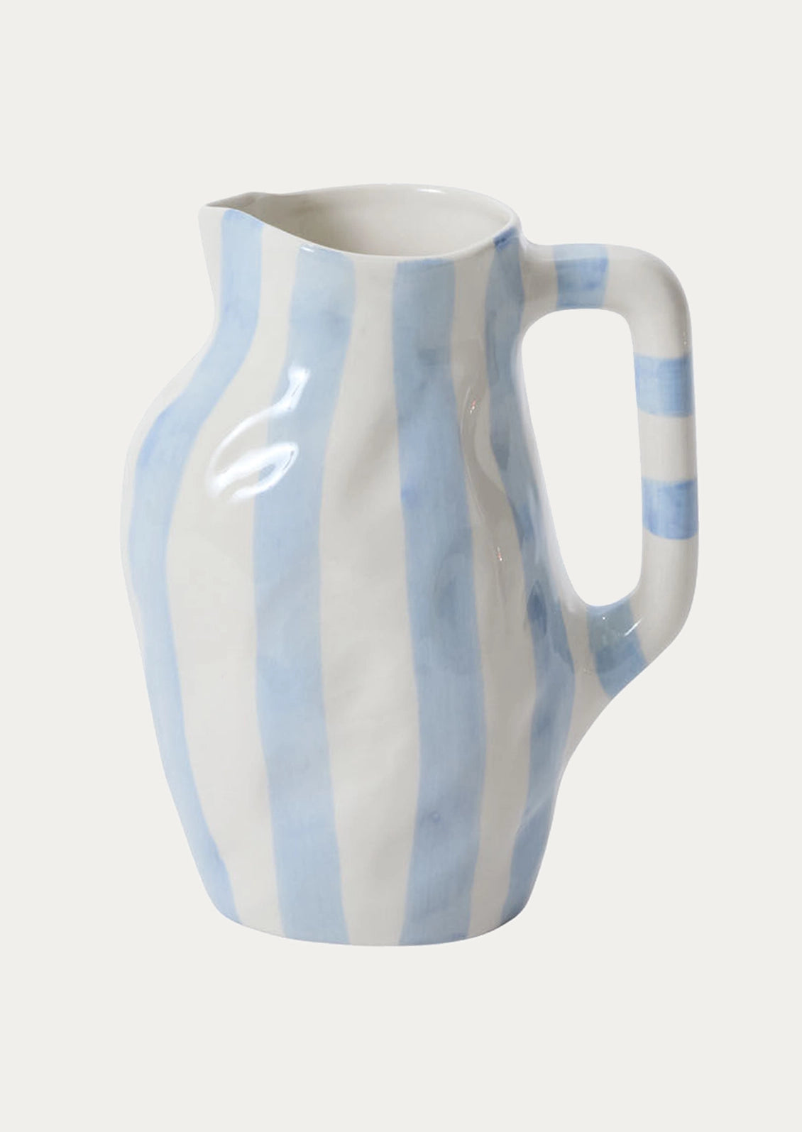 A white ceramic pitcher with vertical light blue stripes, featuring a curved handle and a glossy finish, set against a plain off-white background.
