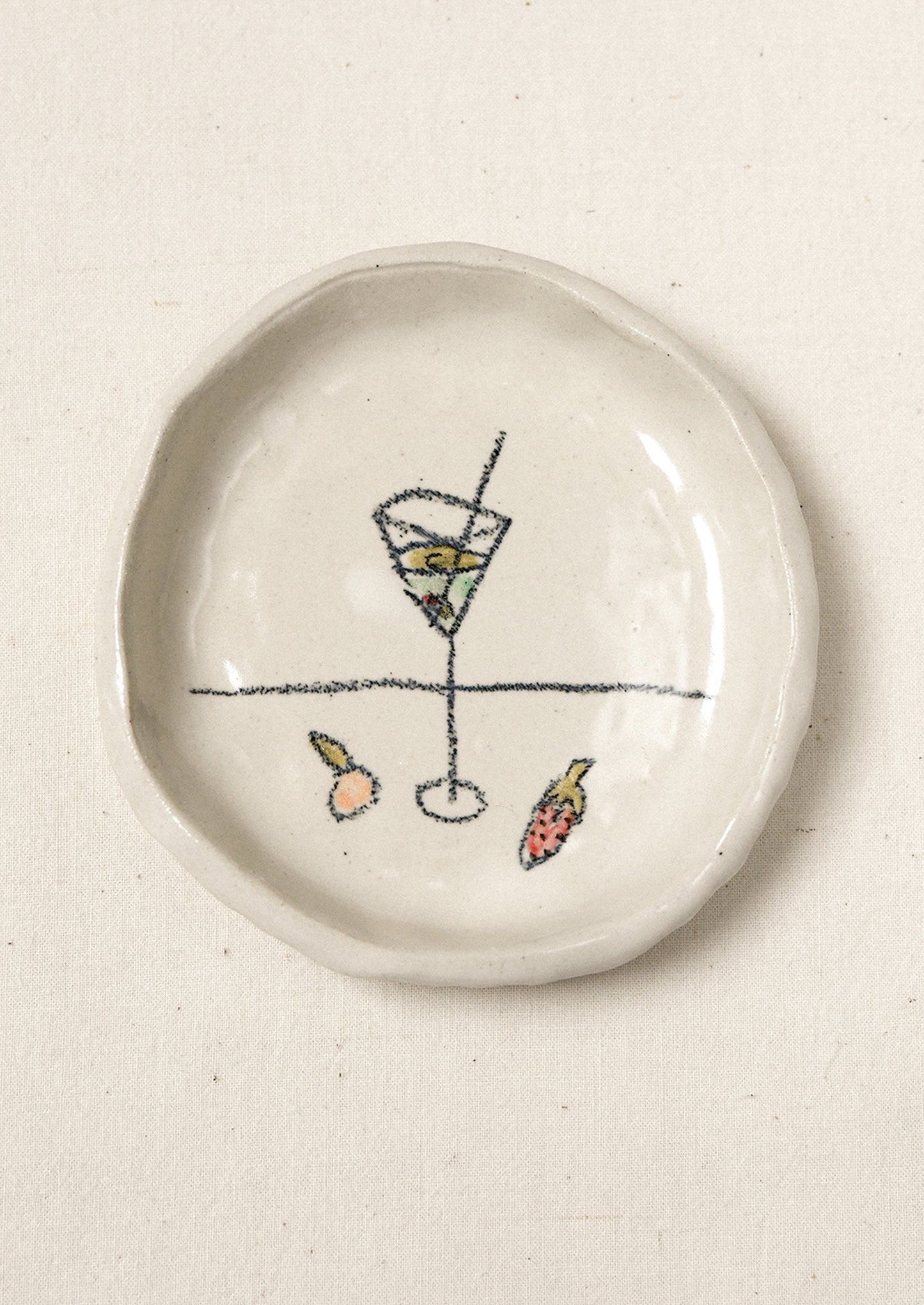 A small ceramic dish with an illustration of a martini glass and fruits.