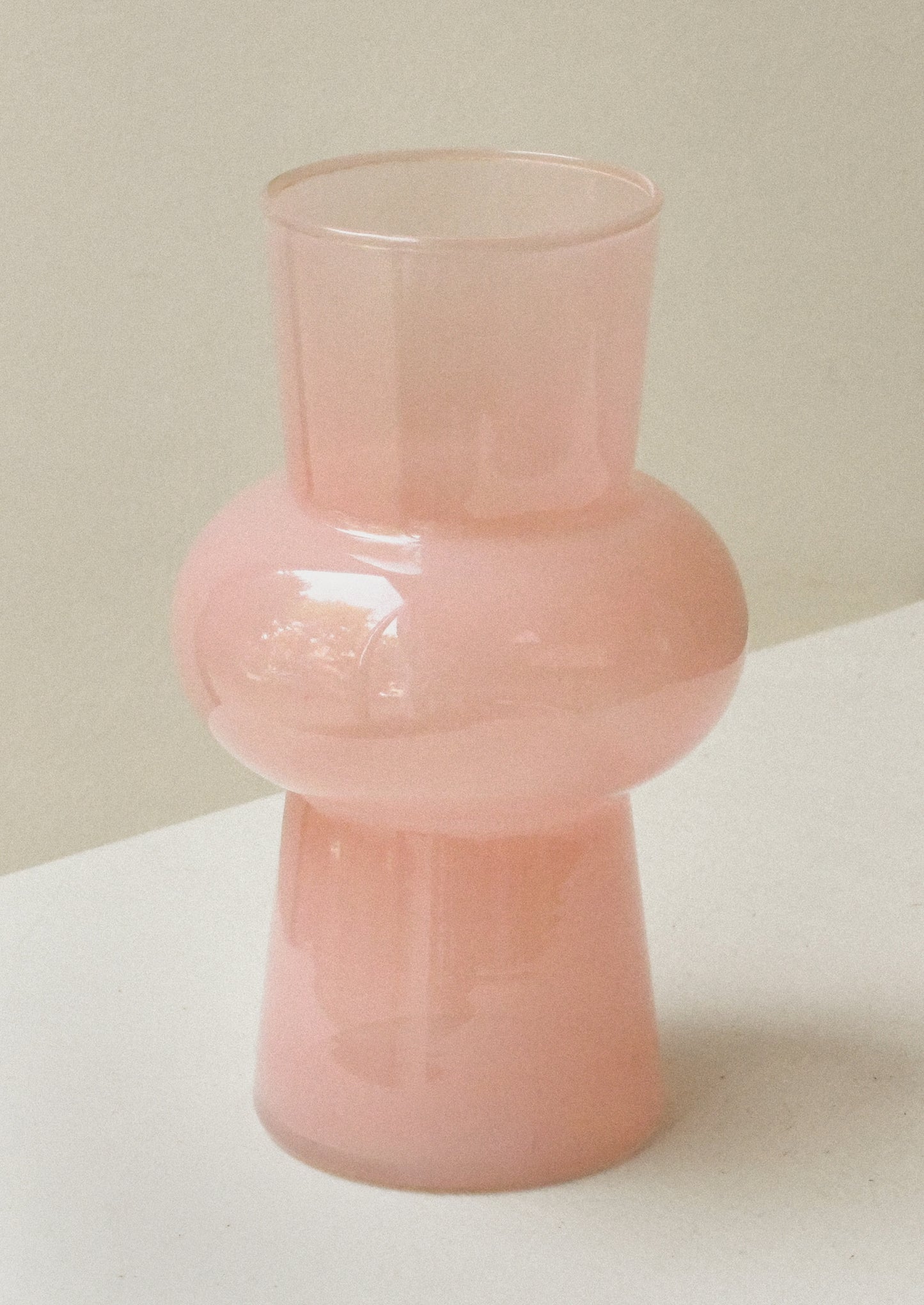 A glass vase with bulbous middle in opaque milky rose hue.