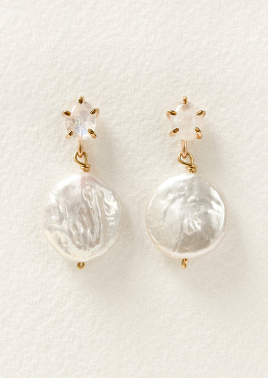 A pair of gold stud earrings feature a moonstone in a pronged setting with a large dangling freshwater coin pearl hanging below.
