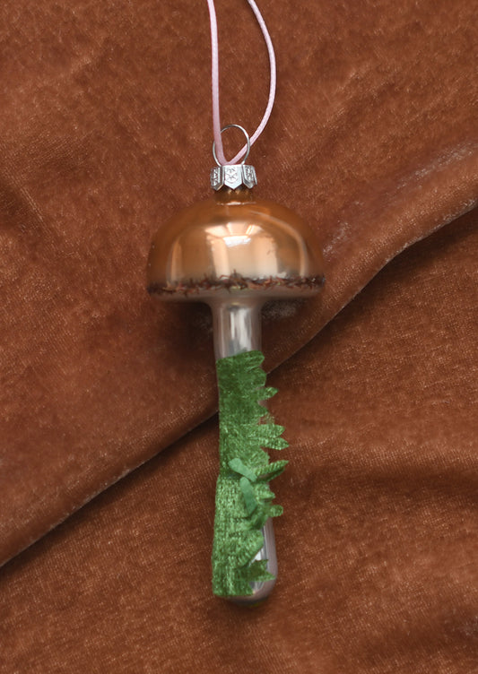 A glass ornament resembling a button mushroom with moss detail.
