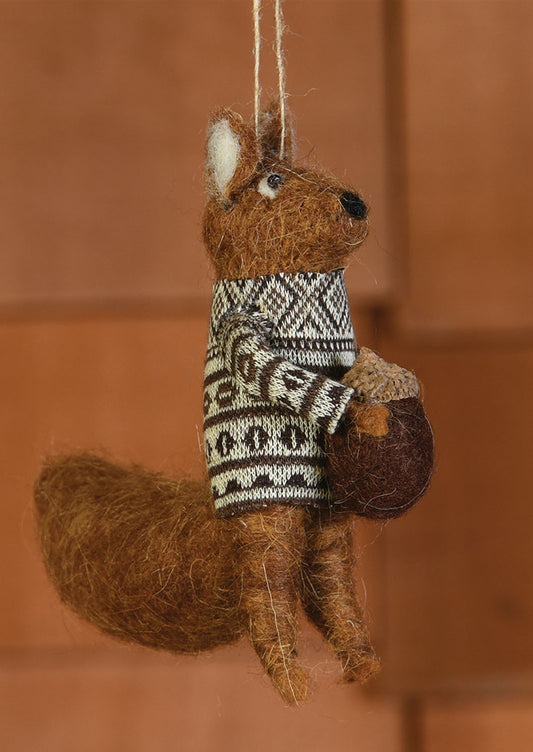 A felted holiday ornament of brown squirrel holding acorn.