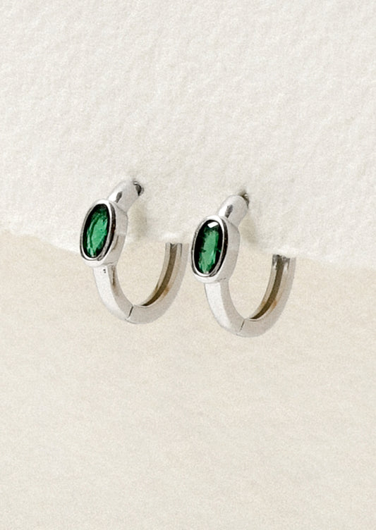 A pair of sterling silver hoop earrings with a green oval gemstone.