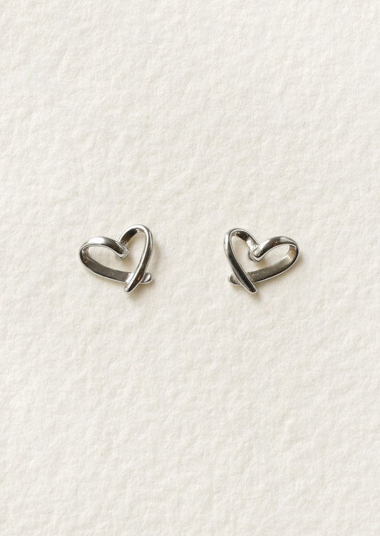 A pair of sterling silver stud earrings that are bent in the shape of hearts.