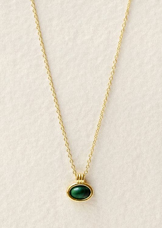 A gold necklace with an oval green gemstone charm.