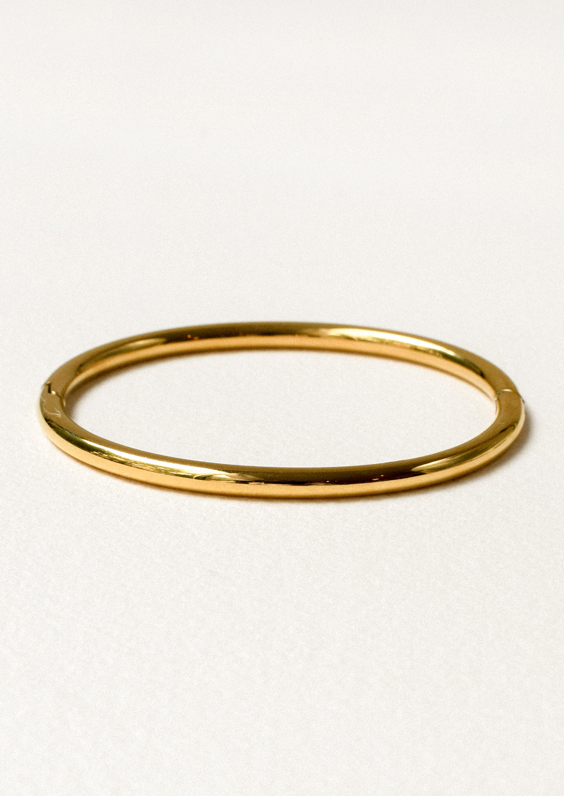 A minimal gold bangle on a white background.