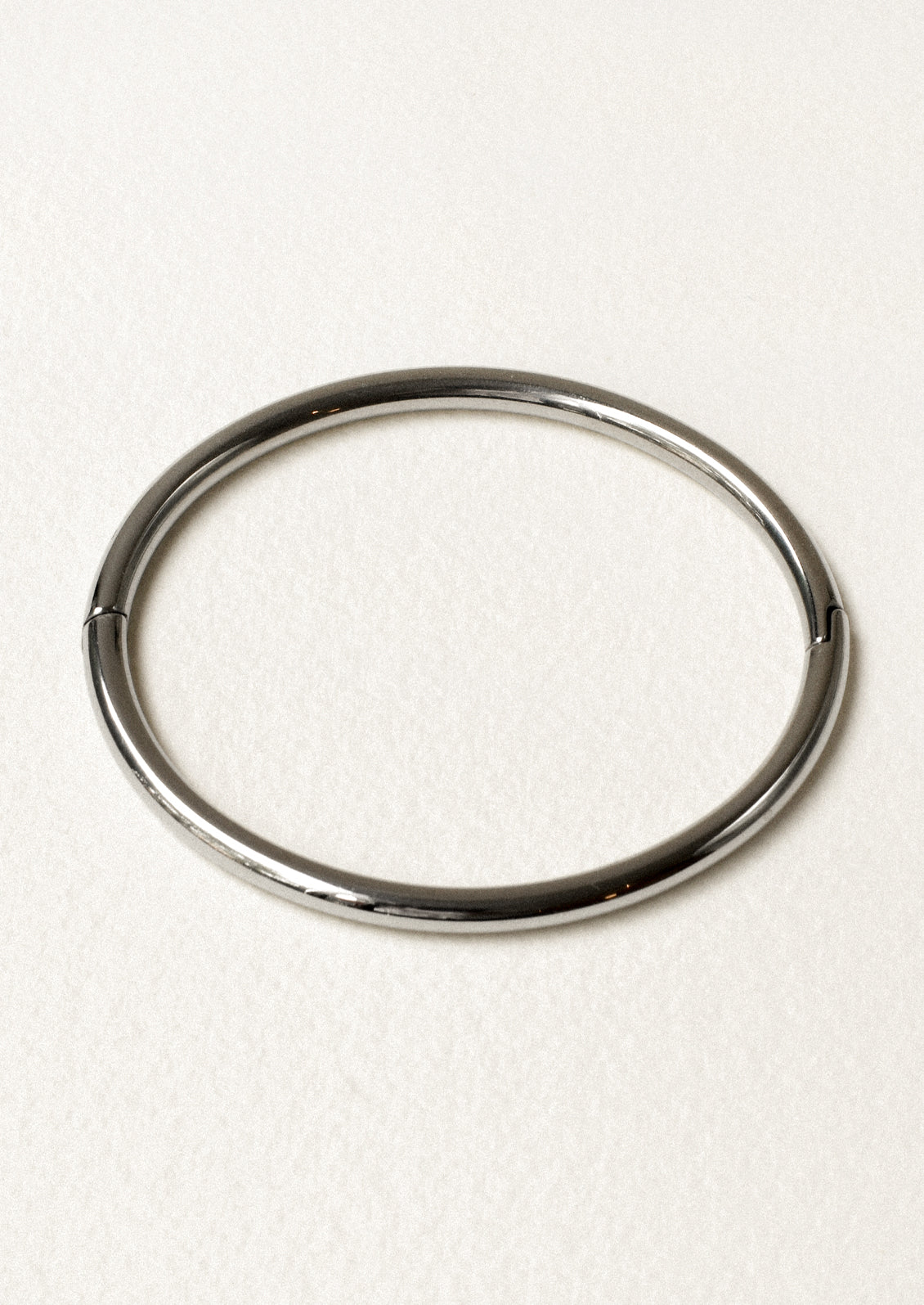 A minimal silver bangle on a white background.