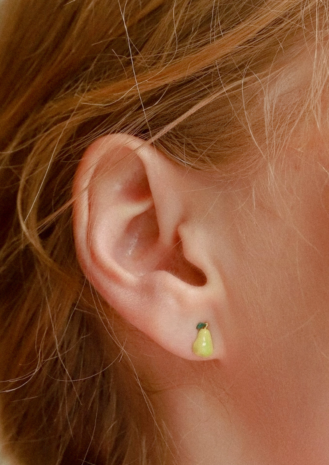A woman wearing a green pear earring.