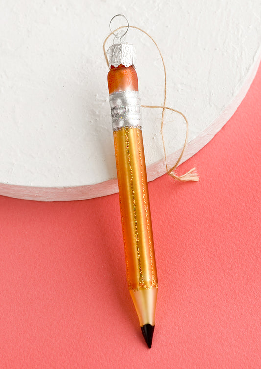 A glass holiday ornament of a pencil.