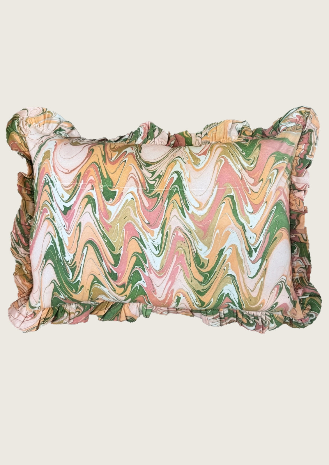 A rectangular ruffled pillow featuring a multicolor wavy marble pattern in shades of green, pink, orange, and cream, set against a solid light beige background.