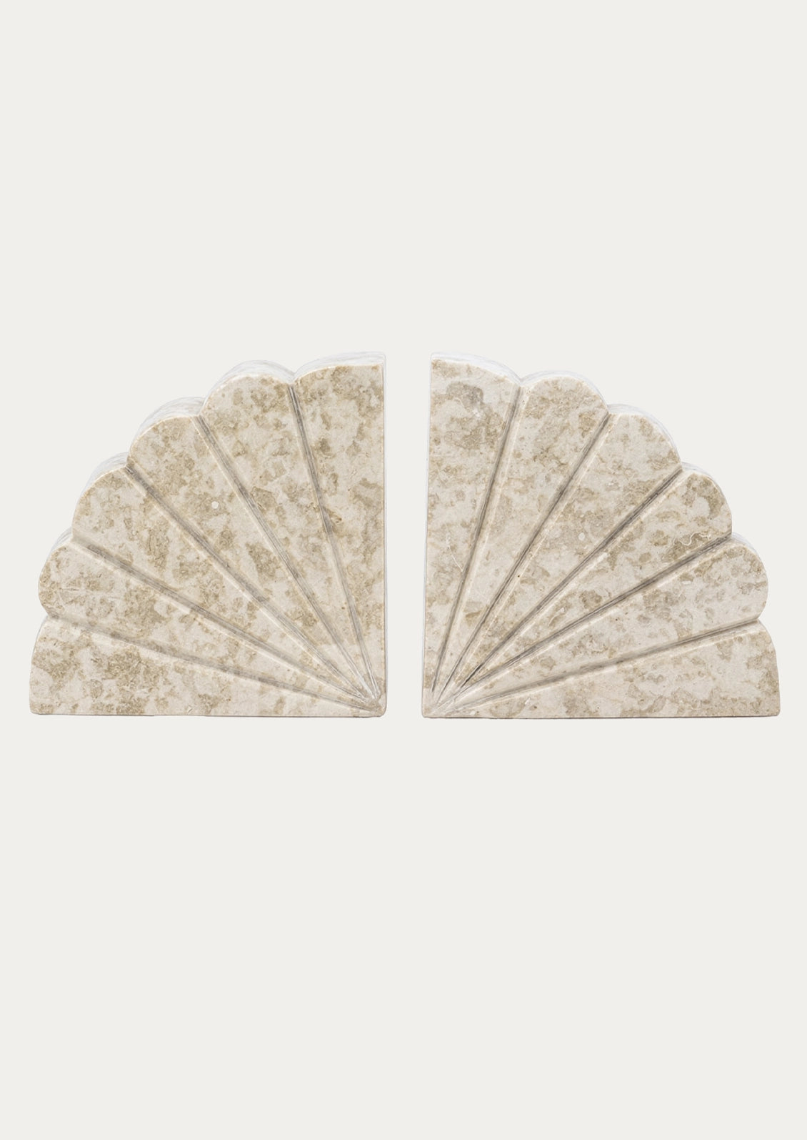 A pair of scalloped fan-shaped bookends made from a textured beige stone with subtle gold veining, displayed against a solid off-white background.