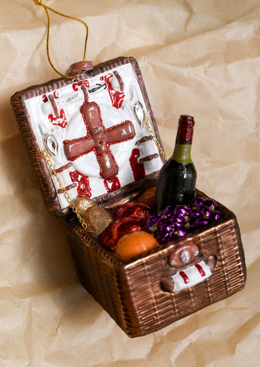 A glass ornament depicting an open picnic basket with wine, bread and fruit.