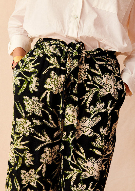 A pair of flowy pants in black with all over cream and green floral print.