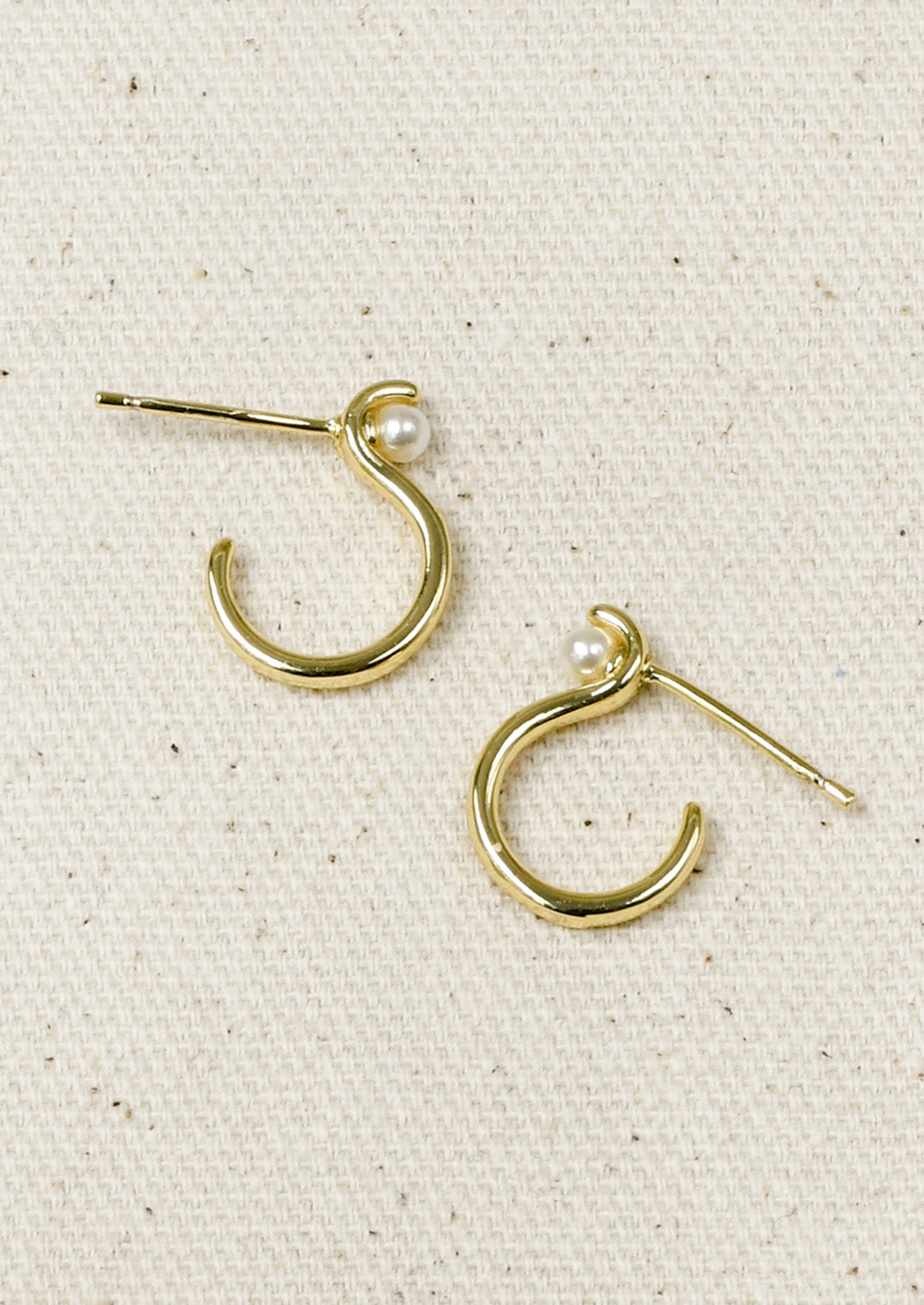 A pair of gold earrings with an "S" shaped design and a single faux pearl at the top.