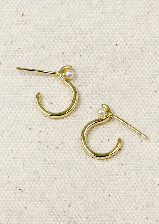 A pair of gold earrings with an "S" shaped design and a single faux pearl at the top.