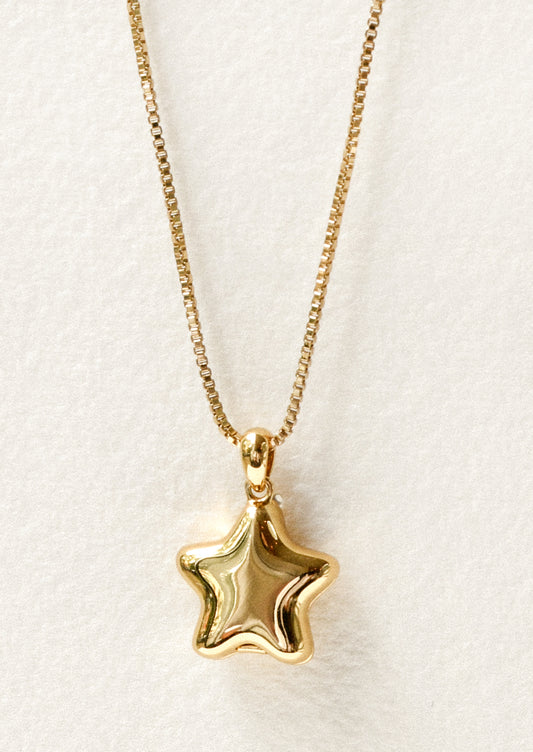 A gold necklace with a puffy star locket pendant.