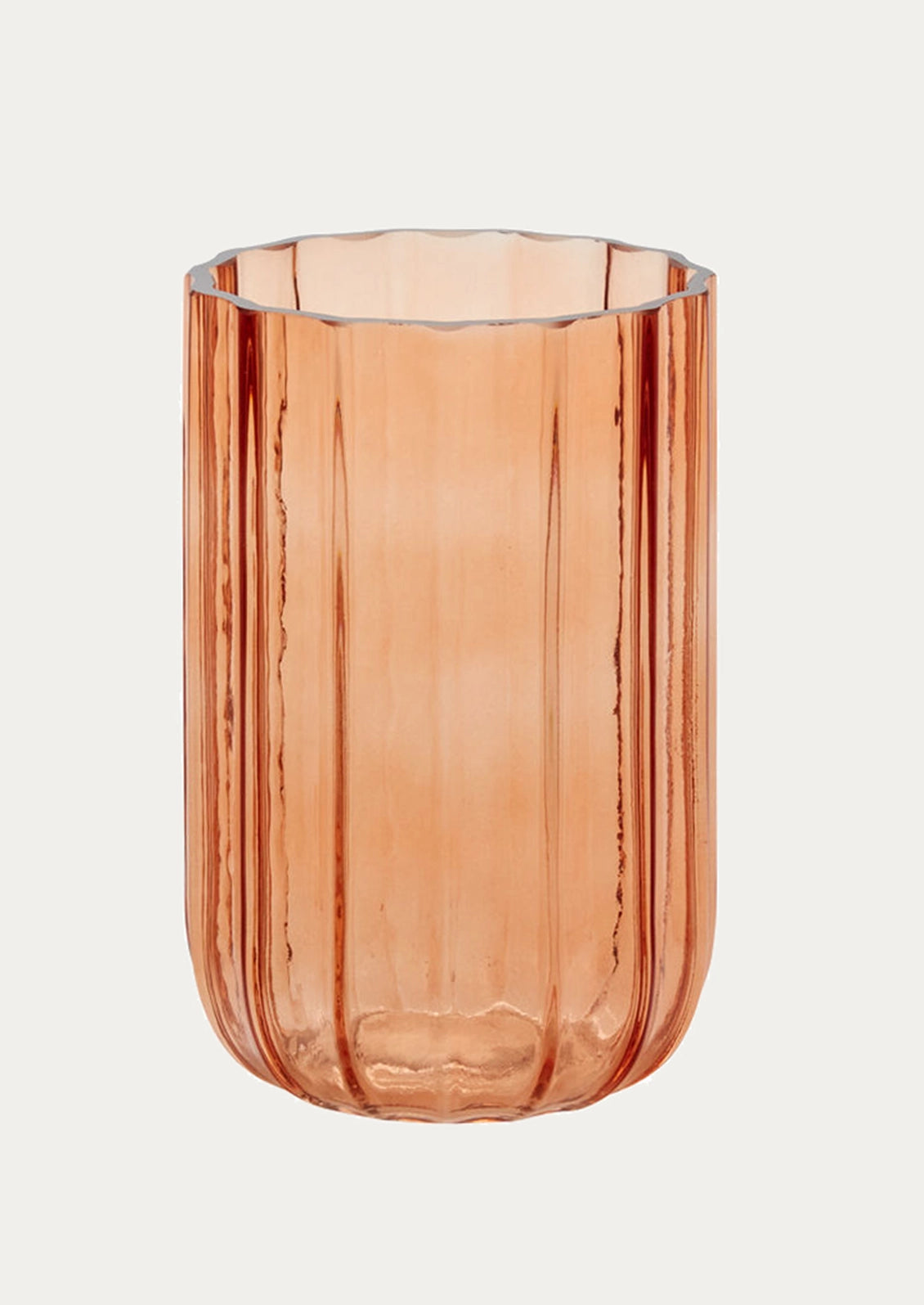 A ribbed fluted glass vase in a translucent peachy pink color.