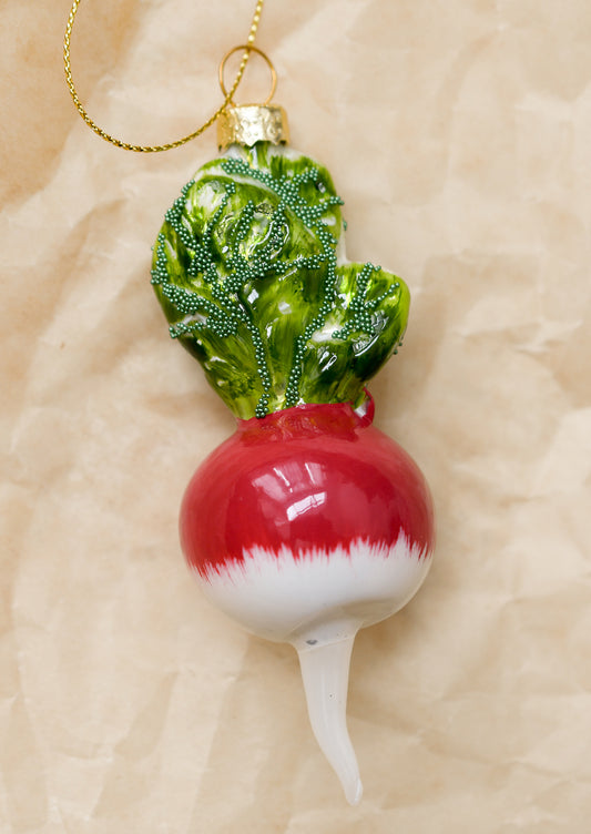 A glass ornament of a red radish with beaded leaves.