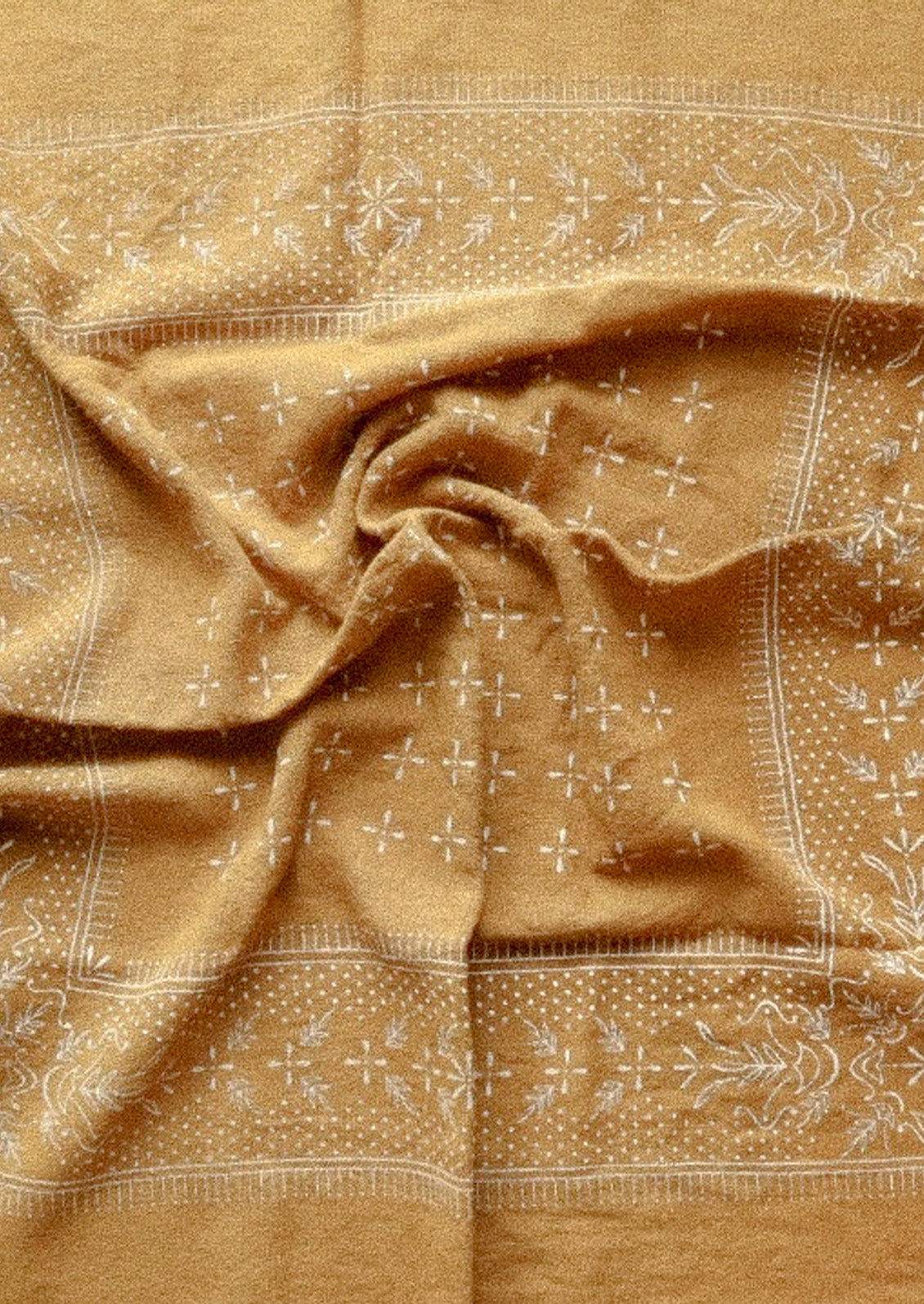 A mustard colored patterned scarf that is bunched up in the center.