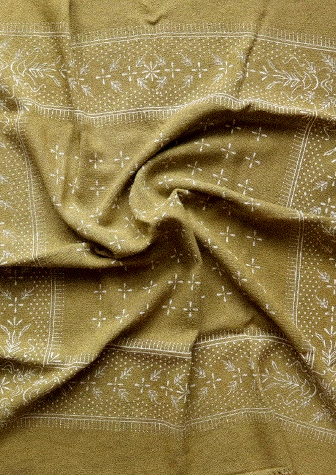 An olive colored patterned scarf that is bunched up in the center.