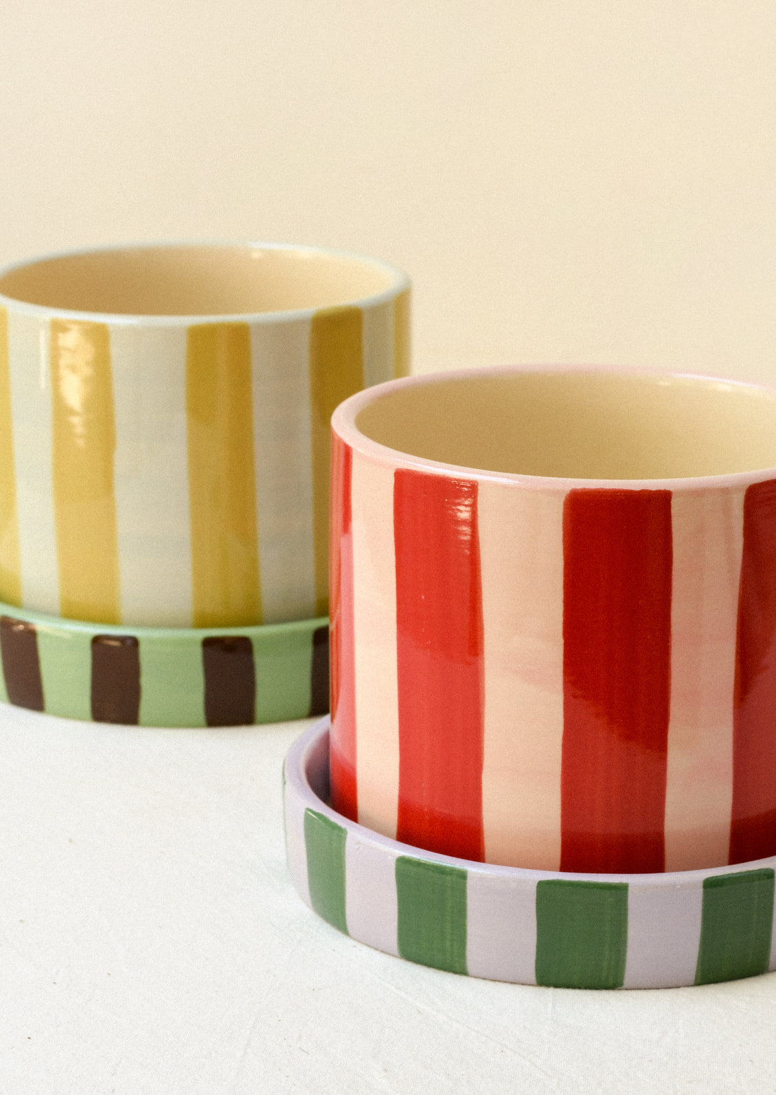 Two colorful striped ceramic planters with striped saucers.