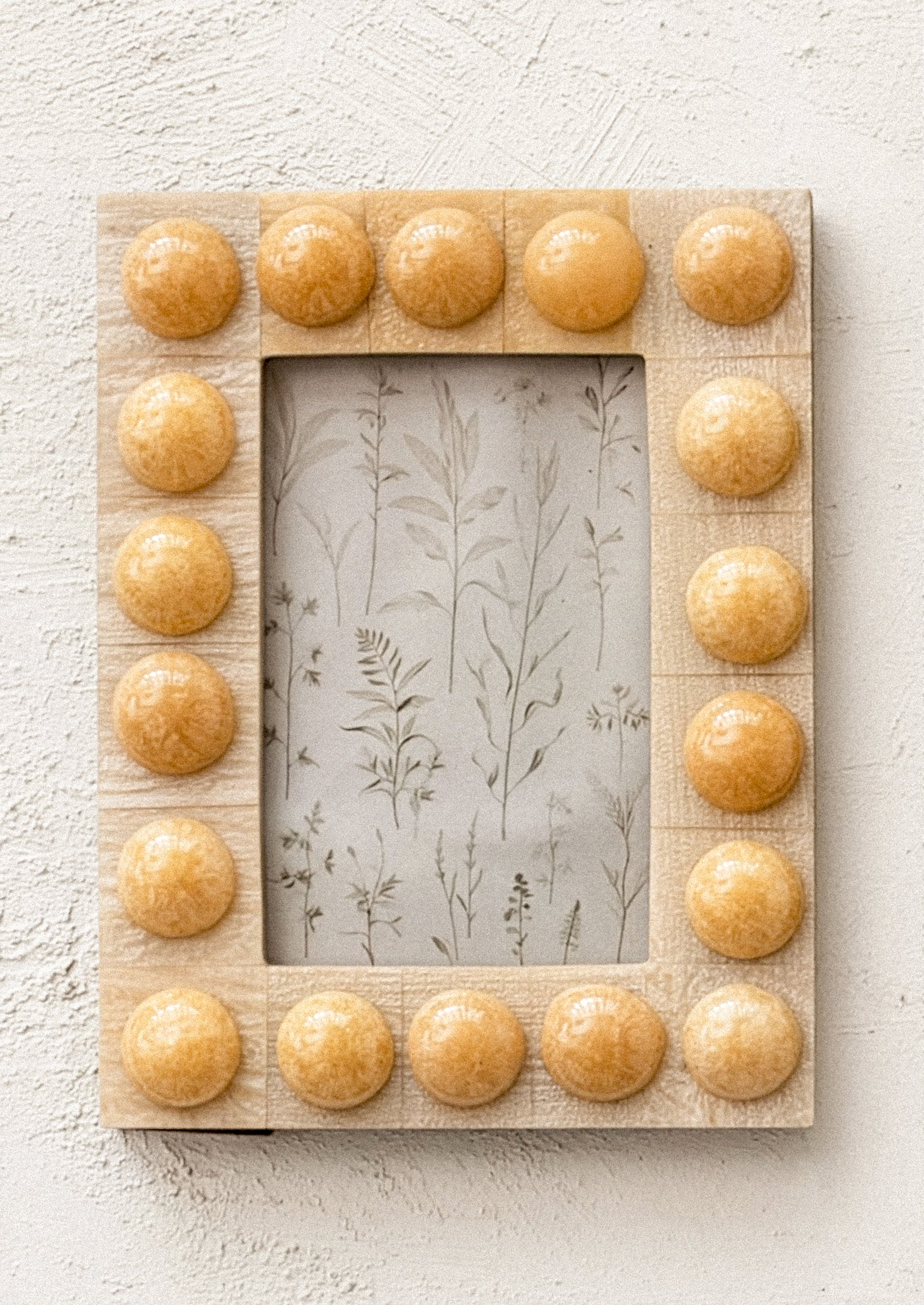 A resin picture frame with bubble hobnail border, in tan color.