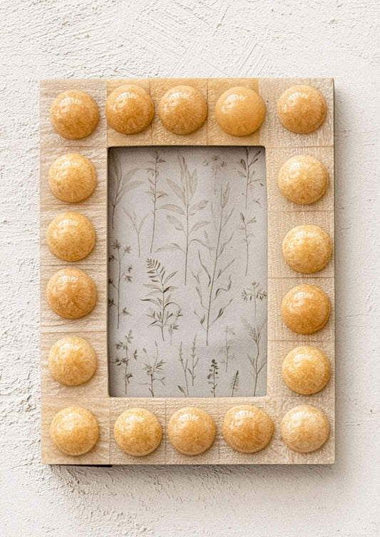 A resin picture frame with bubble hobnail border, in tan color.