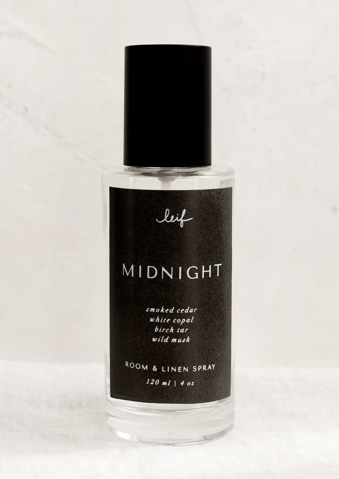 A room spray bottle with printed text on black label.