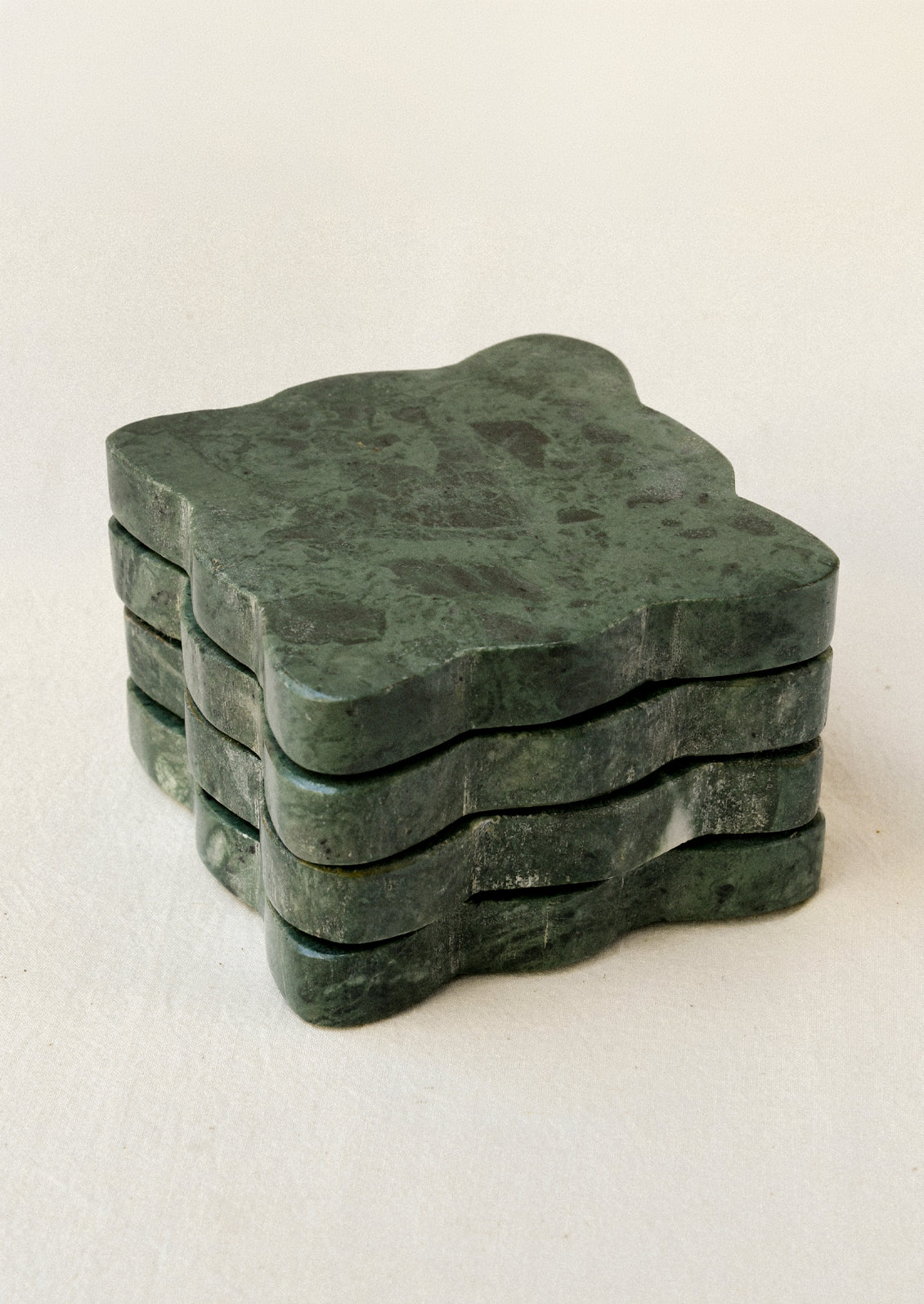 A set of 4 green marble coasters with scalloped edges.