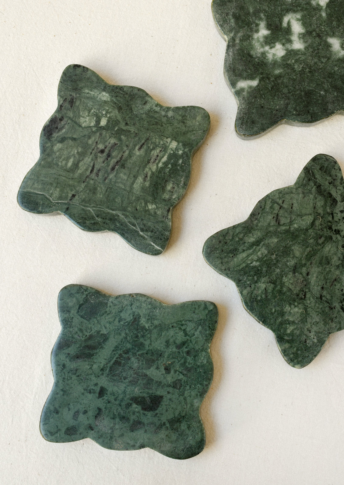 A set of 4 green marble coasters with scalloped edges.