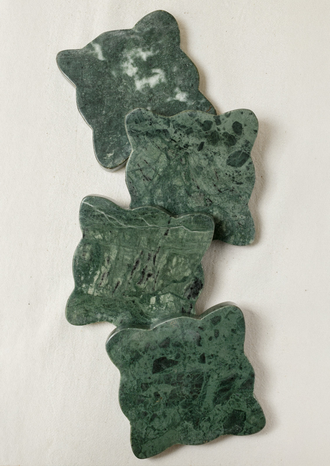 A set of 4 green marble coasters with scalloped edges.