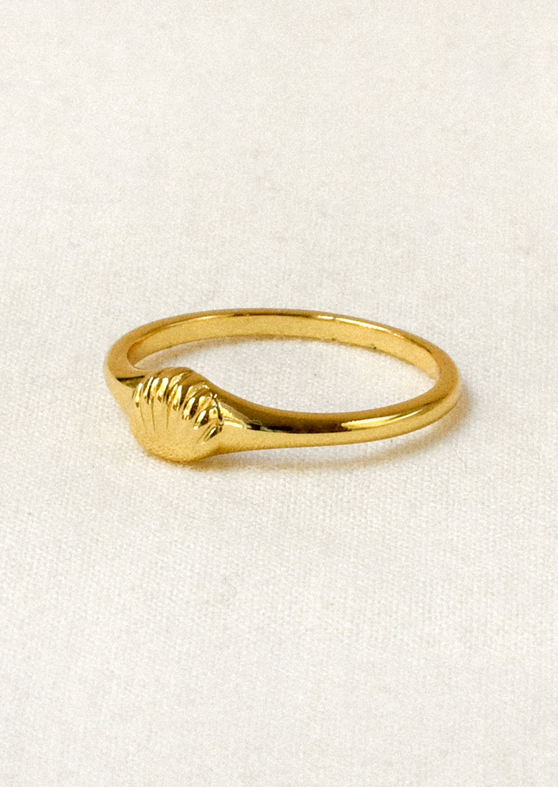 A gold ring with a tiny gold seashell on the front.