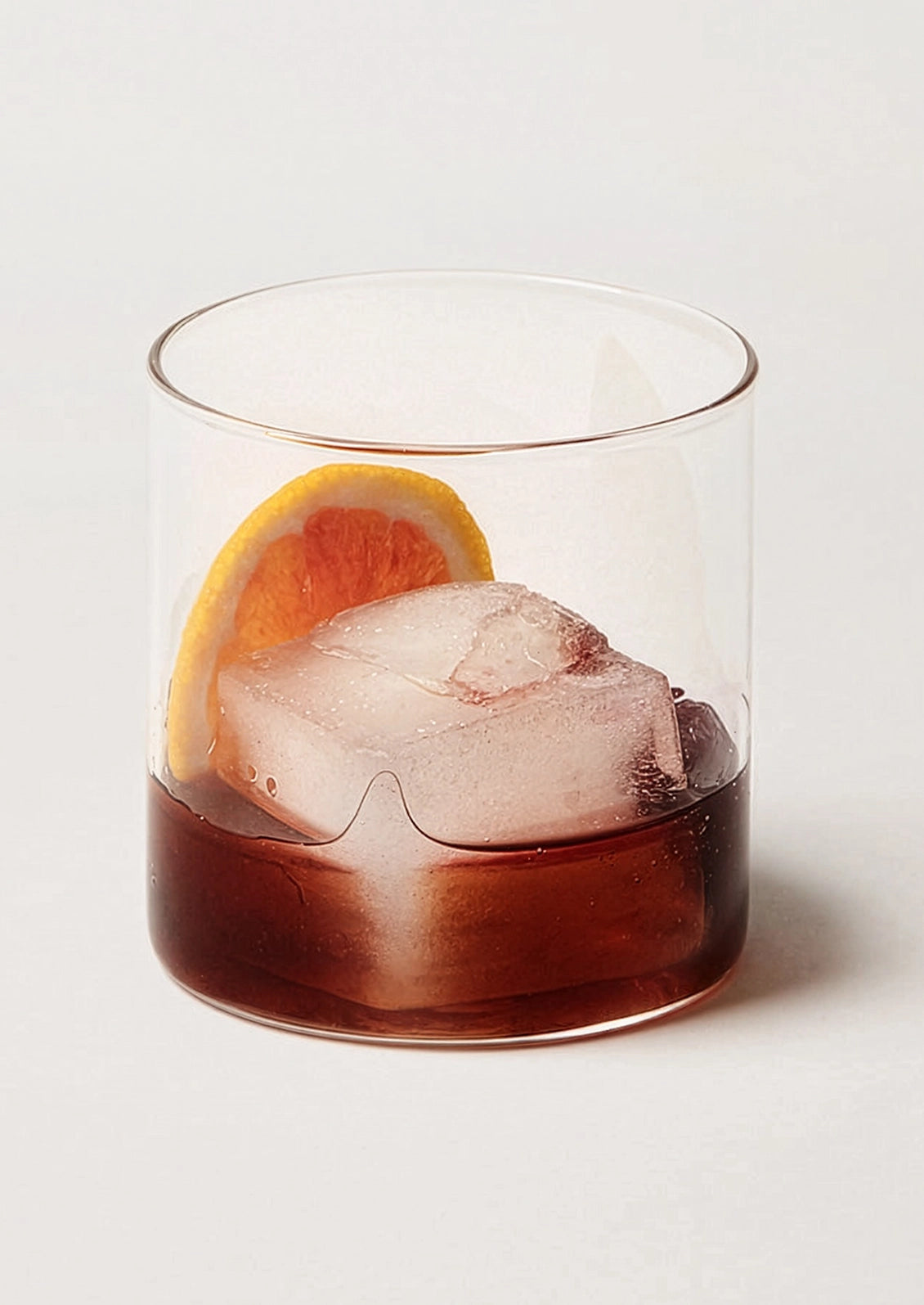 A clear double old fashioned glass with cocktail.